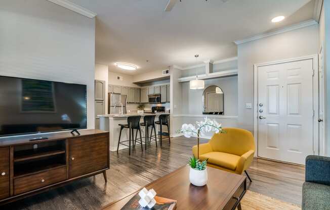 a living room with a tv and a kitchen in the background