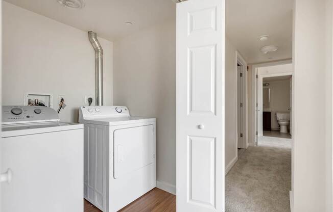 a white washer and dryer in a room with a hallway and a bathroom