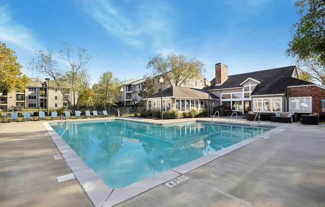A large swimming pool in front of a building with a clear blue sky above.