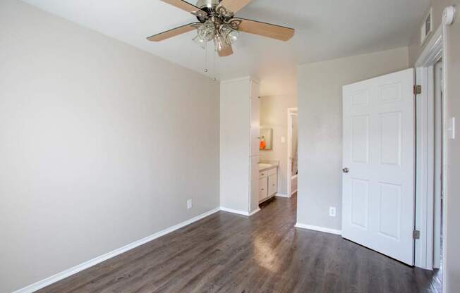 A room with a ceiling fan and wooden floors.