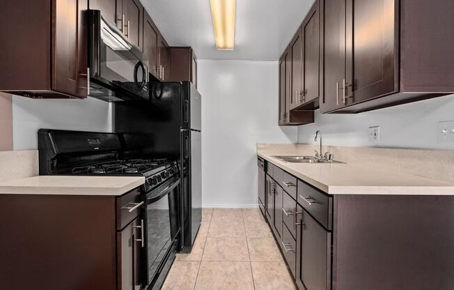 a kitchen with dark cabinets and a black stove top oven