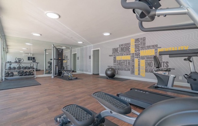 the gym is equipped with exercise machines and weights at The Flats on Addison, Sherman Oaks