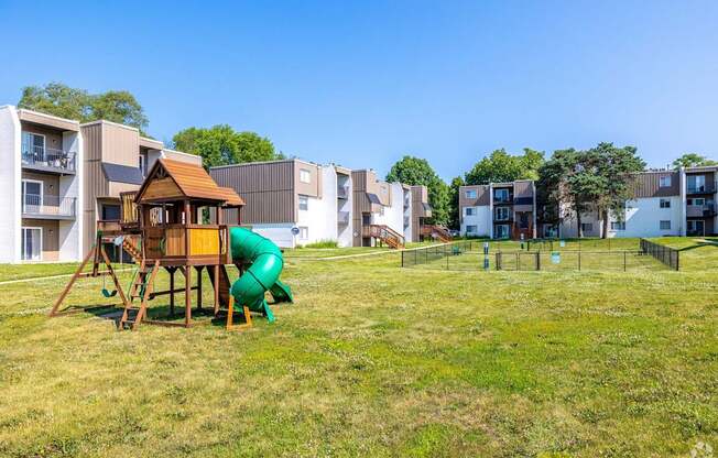 a playground in a park in front of apartment buildings