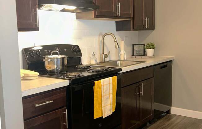 A kitchen with a black stove top oven and wooden cabinets.