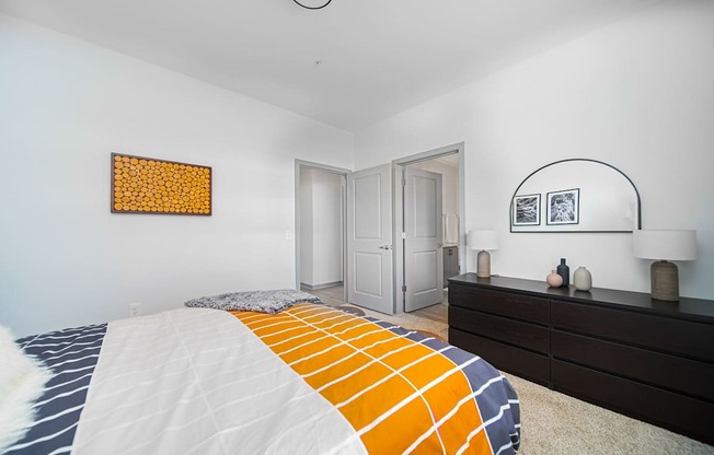 A bedroom with a bed, dresser, and two framed pictures on the wall.