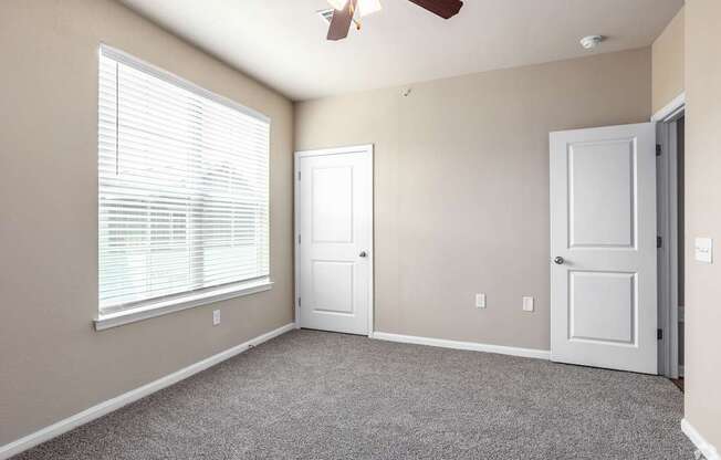 an empty living room with a window and a ceiling fan