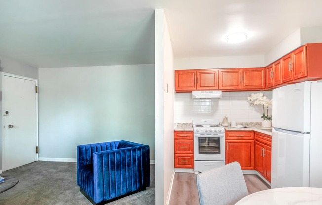 a kitchen and living room with white appliances and orange cabinets