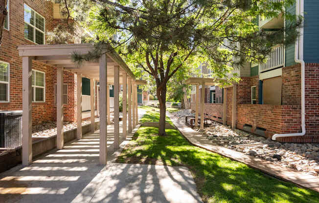 a sidewalk in front of a brick building with trees