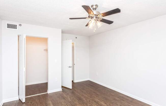 A room with a ceiling fan and wooden floors.