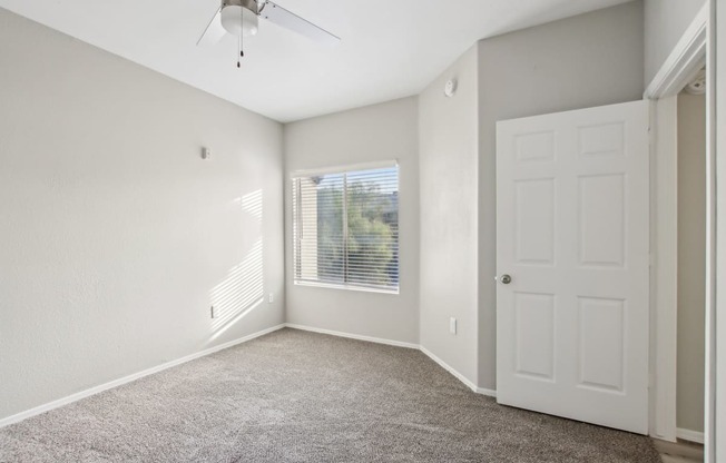 A room with a ceiling fan and a door.