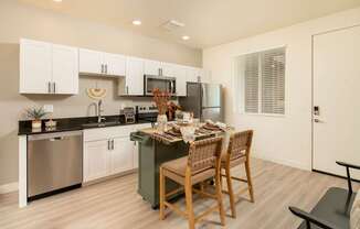 A kitchen with a table and chairs in the middle.