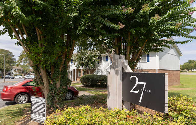 A sign with the number 27 on it is in front of a tree.