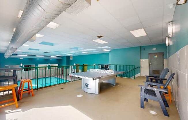 A room with a ping pong table and chairs.