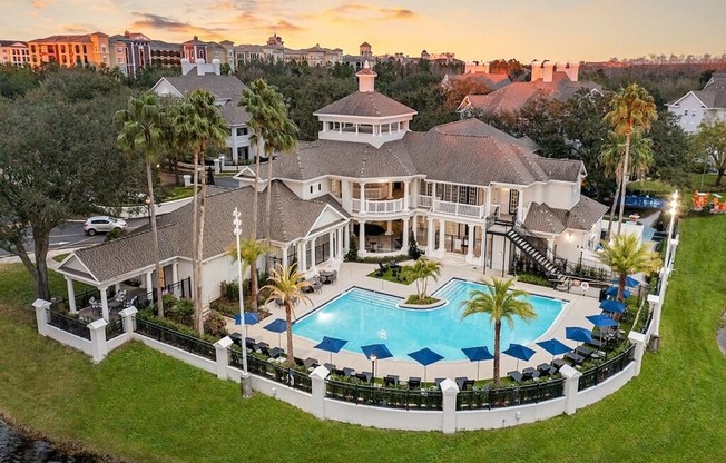 an aerial view of a mansion with a large swimming pool