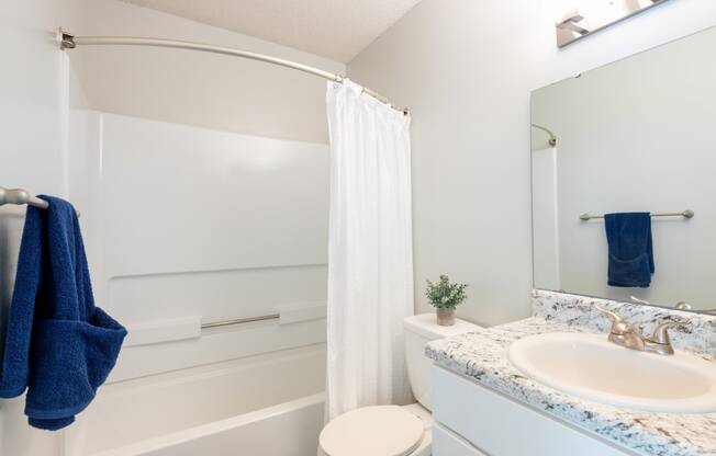 a bathroom with a white shower curtain and a white toilet next to a sink with a blue