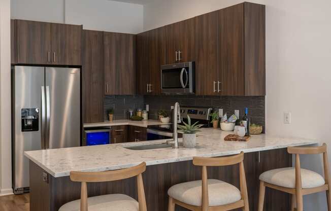 a kitchen with a marble counter top and three stools  at The Clearing at ONE28, Olathe, KS, 66062