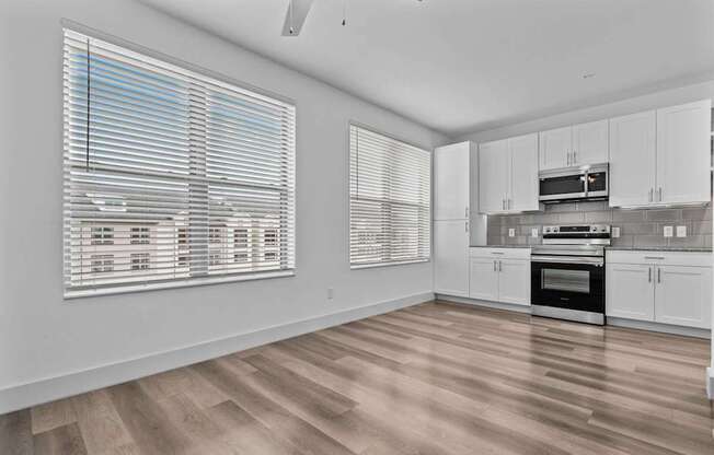 an empty kitchen with white cabinets and a large window