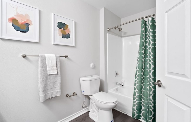 a bathroom with a green shower curtain and a white toilet