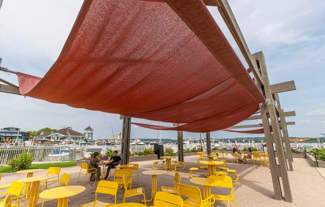 A red canopy over yellow chairs and tables.