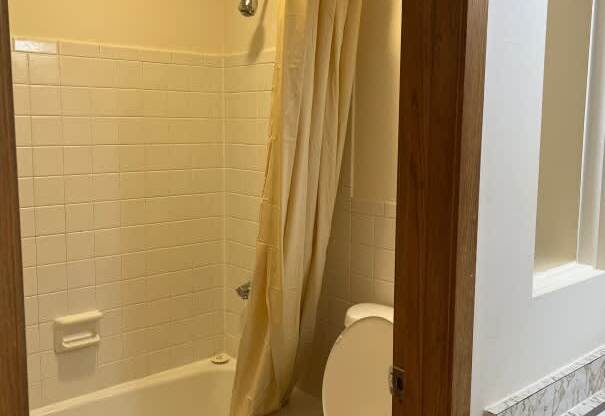 A white toilet in a bathroom with a shower curtain.