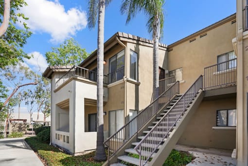 an apartment building with stairs and palm trees