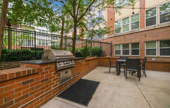 A patio with a grill and chairs.