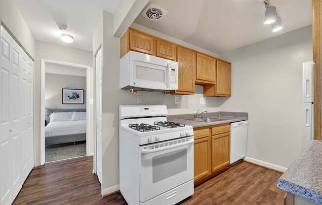 A small kitchen with a white stove and wooden cabinets.