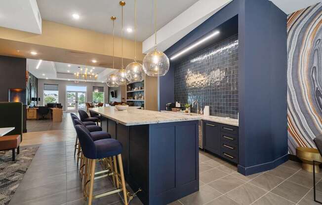 A kitchen with dark blue cabinets and a bar area with stools.