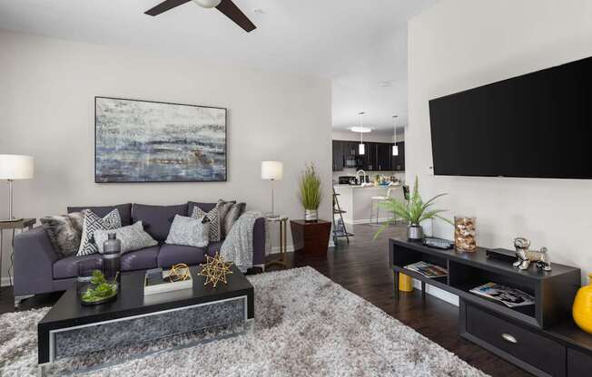 A modern living room with a grey couch, a coffee table, and a painting on the wall.