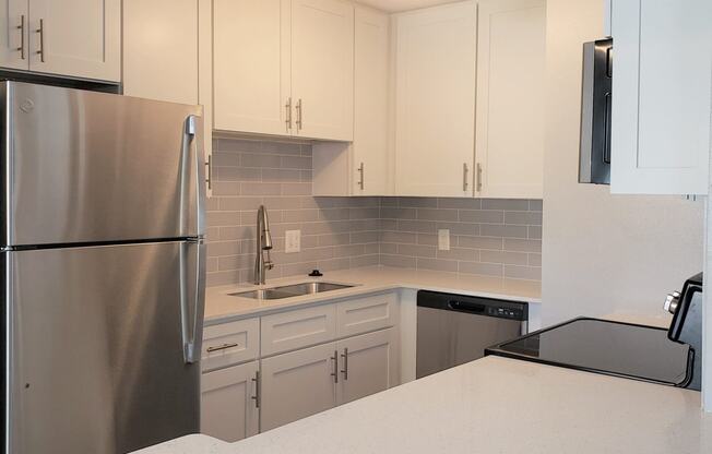 a kitchen with white cabinets and a stainless steel refrigerator