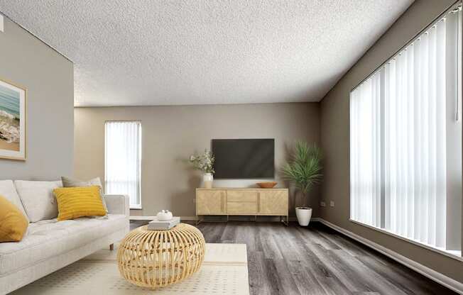 A living room with a grey couch, a wooden coffee table, a flat screen TV, and a potted plant.