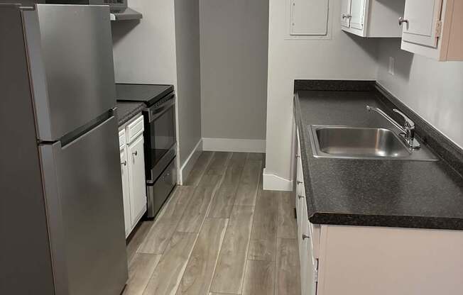 A kitchen with a refrigerator, sink, and cabinets.