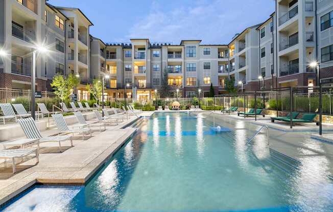 an apartment building with a swimming pool and lounge chairs at The Hendrix, Atlanta