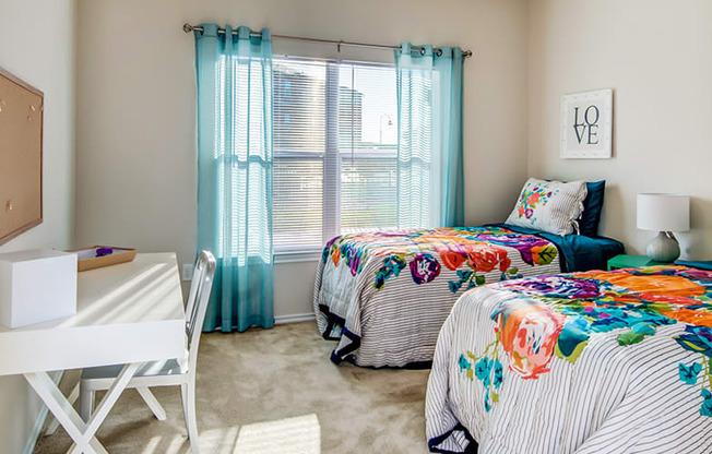 a bedroom with two beds and a desk at Villa Espada Apartments, Texas