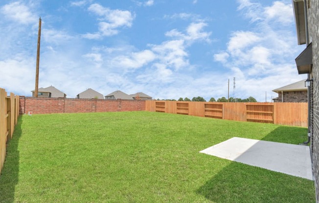 Two-BR Homes for Rent in Katy, TX - Villas at Sunterra - Backyard with Well-Maintained Green Grass and a Wooden/Brick Fence