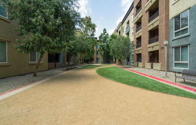 A long, narrow, dirt pathway leads between two rows of apartment buildings at The Kitt at Warner Center Apartments, Woodland Hills, California