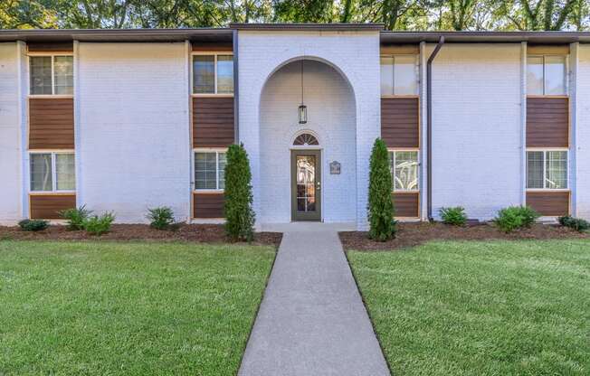 the front of a building with a sidewalk and grass