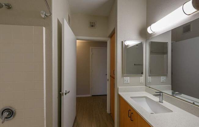 A bathroom with a sink, mirror, and shower.