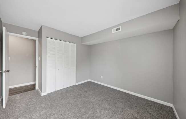 an empty room with carpet and a door to a closet at The Avalon Apartment Homes, Chesterfield, MO