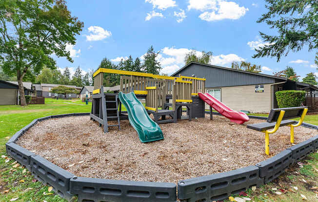 A playground with a green slide and a red slide.