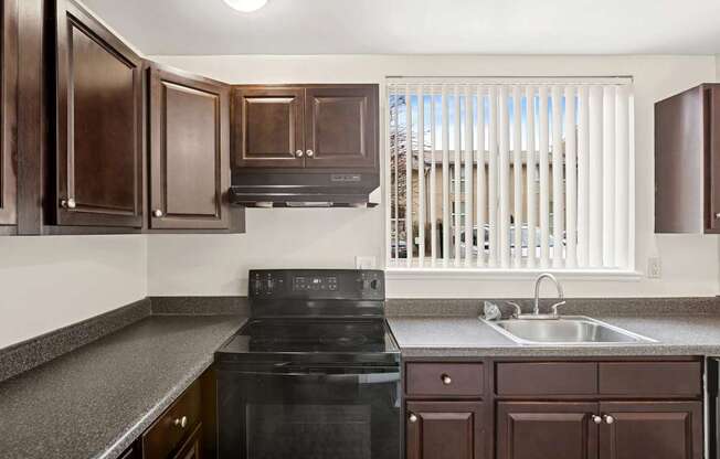 A kitchen with dark brown cabinets and a black stove top oven.