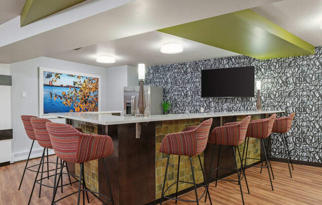 a kitchen with a bar with chairs and a television