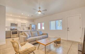 A living room with a couch, chair, and a fan.