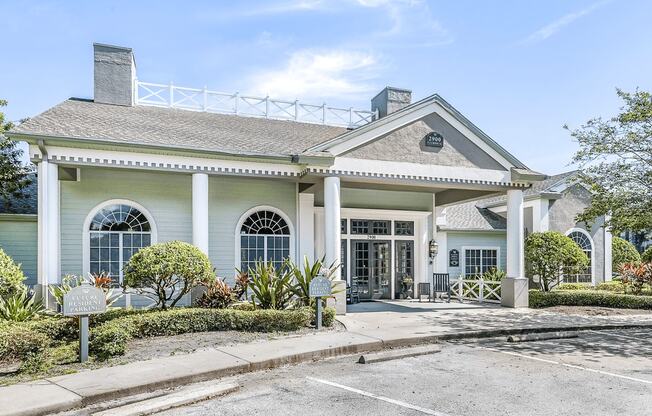 Clubhouse and leasing office exterior with parking lot and native landscaping