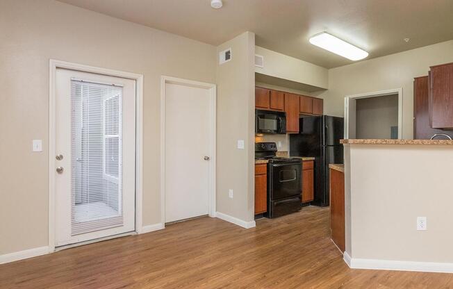 Living room with door to private balcony/patio and view of kitchenÂ 