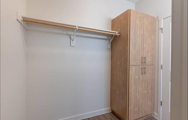 A room with a white wall and a wooden cabinet with a shelf above it at Forestplace Apartment Homes, Forest Grove, 97116