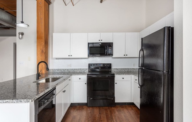 a kitchen with white cabinets and black appliances and granite counter tops