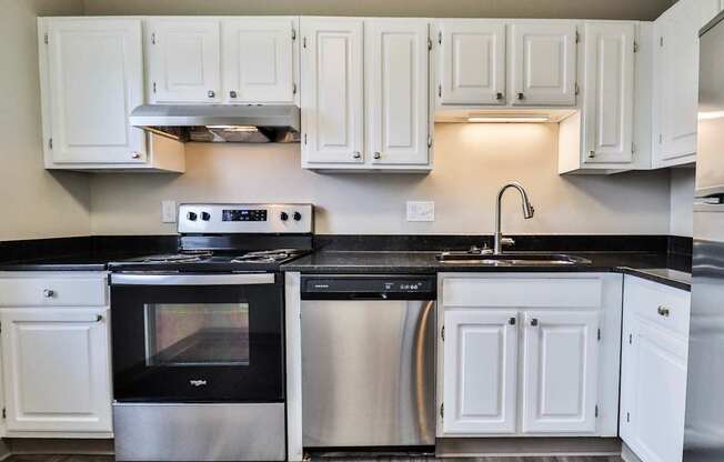 A modern kitchen with white cabinets and black countertops.