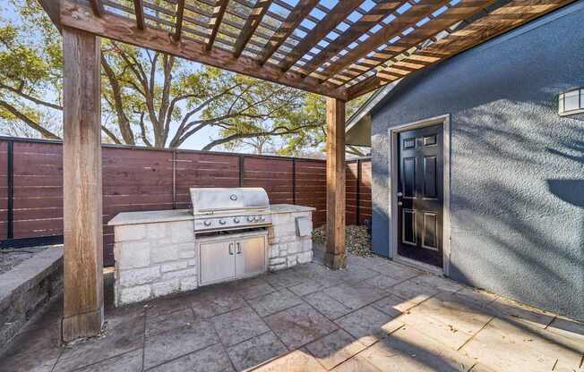 A patio with a grill and a pergola.