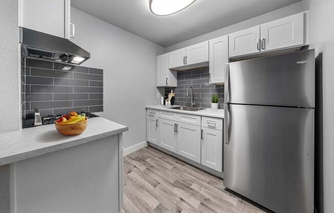 A kitchen with a refrigerator, sink, and cabinets.